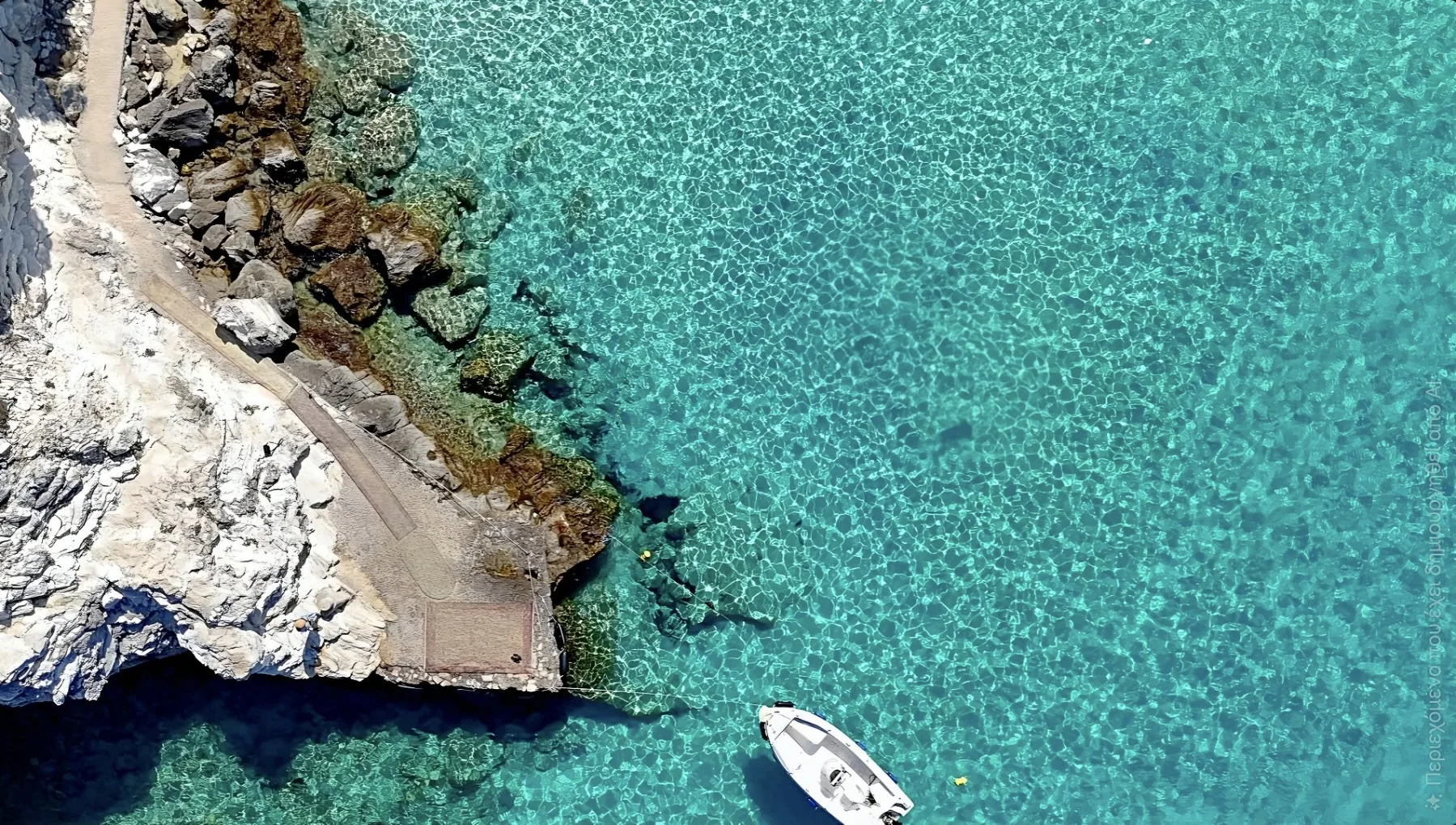Aerial view of the turquoise Ionian Sea beside the rocky Paxos coastline